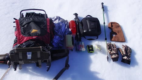 Nature-and-wildlife-photography-and-outdoor-gear-from-a-backpack-on-display-in-the-snow-during-a-winter-on-Kodiak-Island-Alaska