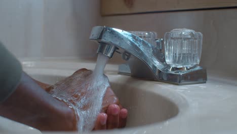 Hochdruckwasser-Sprudelt-Auf-Einem-Schwarzen-Mann,-Der-Die-Hände-Im-Waschbecken-Spült---Zeitlupe