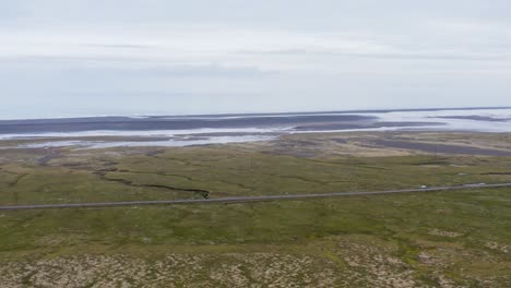 Flying-past-rock-ridge-revealing-Iceland-ring-road-and-Atlantic-Ocean-shore