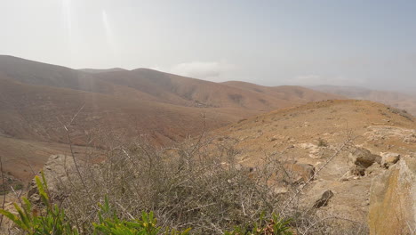 Mountain-Desert-Landscape-View-From-Hillside-Slope-With-Few-Growing-Plants-In-Fuerteventura,-Canary-Islands,-Spain