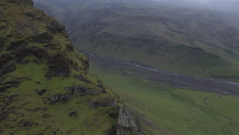 Dramatic-green-grass-rock-valley-with-river-in-Iceland-highlands,-cloudy-day