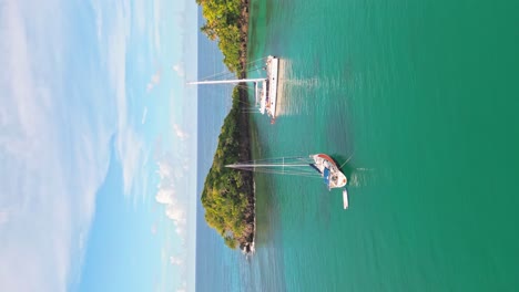 Vertical-aerial-forward-flight-approaching-luxury-catamaran-in-tropical-bay-during-summer---Playa-Bonita,Dominican-Republic