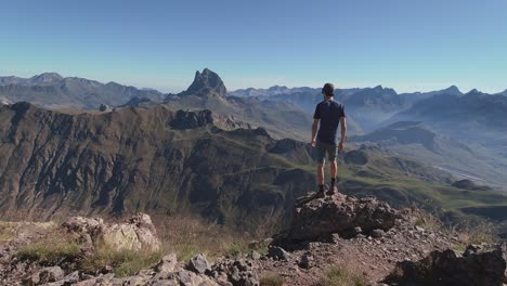 Young-hiker-standing-on-the-edge-of-Anayet-peak-and-enjoying-the-views-of-French-Pyrenees-and-Midi-D-ossau-peak