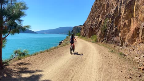 Woman-riding-bike-along-beautiful-lake-side-trail