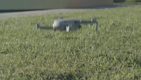 A-drone-takes-off-in-slow-motion,-starts-from-the-green-lawn-and-rises-to-the-sky