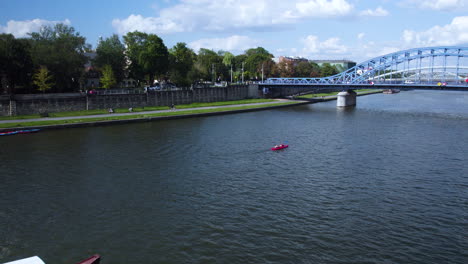 Aerial-view-of-kayak-paddling-and-boat-cruising-on-Vistula-River-in-Krakow,-Marszałek-Józef-Piłsudski-Bridge,-Turtle-Bridge,-Poland