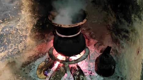 Moroccan-couscous-cooking-on-a-couscoussier-steamer-to-steam-it
on-a-wooden-fire-in-a-fireplace,-smoke-and-flame-surround-the-pot-3