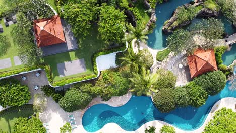 Aerial---birdseye-shot-of-beautiful-resort-with-pools-and-waterslides-surrounded-by-lush-jungle
