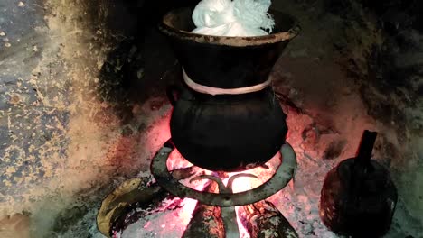 Moroccan-couscous-cooking-on-a-couscoussier-steamer-to-steam-it
on-a-wooden-fire-in-a-fireplace,-smoke-and-flame-surround-the-pot-2