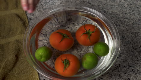 Hände-Entfernen-Grüne-Paprika,-Rote-Tomaten-Und-Grüne-Limette-Aus-Der-Glasschüssel-Mit-Wasser