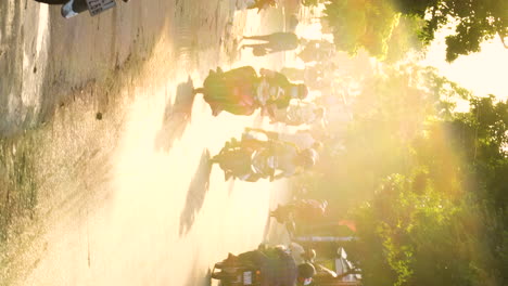 Busy-Vietnam-street-with-motorbikes-during-golden-sunset,-vertical-video
