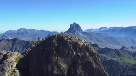 Aerial-view-of-Anayet-mountain-range-peak-with-people-standing-on-top-and-views-of-Midi-D-Ossau-peak-in-Spanish-and-french-Pyrenees-in-Summer-morning