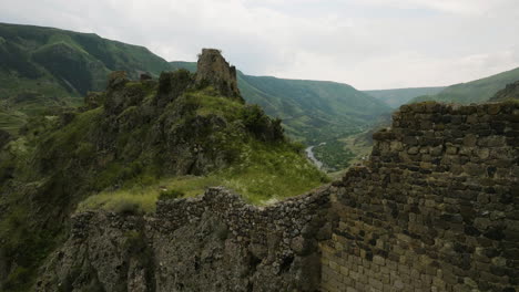 Drone-Ascending-Over-Ancient-Ruins-Of-Tmogvi-Fortress-Revealing-Mtkvari-River-In-Georgia