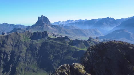 Aerial-view-of-Anayet-mountain-range-peak-with-man-stangin-on-top-in-Spanish-and-french-Pyrenees-in-Summer-morning