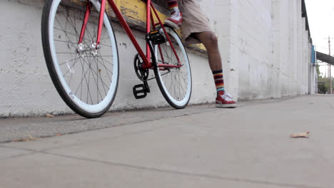 Slider-shot-of-a-black-man-with-his-red-bicycle-in-an-industrial-setting
