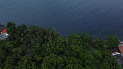 Drone-tilt-up-on-the-shoreline-at-tropical-village-facing-ocean