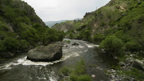 Río-Rocoso-Que-Fluye-En-Las-Grandes-Montañas-Del-Cáucaso-En-La-Base-Del-Monte-Del-Castillo-De-Tmogvi,-Región-De-Samtskhe-javakheti,-Georgia