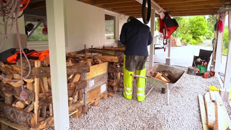 Man-standing-under-his-balcony-and-throwing-freshly-cut-firewood-into-boxes-for-drying-and-storing-before-winter