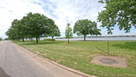 POV-while-slowly-driving-thru-a-green-space-park-with-the-Great-River-Trail-along-the-Mississippi-River-in-the-Quad-Cities,-Illinois