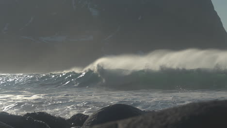 Waves-break-in-slow-motion-on-Unstad-beach-with-a-rugged-mountain-in-the-background