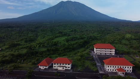Tilt-down-above-school-with-Mount-Agung-Bali-background,-aerial