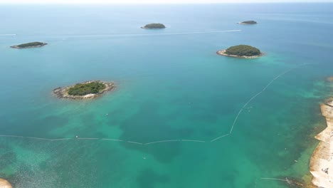 Drone-flight-in-Croatia-over-an-archipelago-of-5-small-islands-above-the-calm,-turquoise-blue-Adriatic-Sea