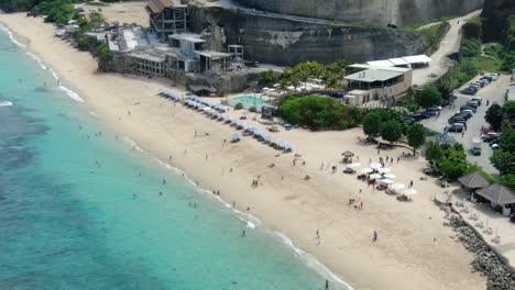 Beautiful-aerial-view-of-some-visitors-sunbathing-at-sunset-on-Melasti-Beach-in-South-Bali,-Indonesia