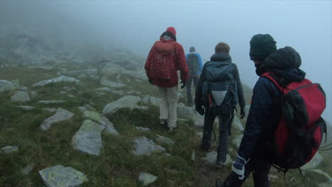 Walk-in-the-morning,-alpinists-are-equiped-with-backpacks,-vests-and-go-through-a-fog-on-a-small-Gravel-path,-Switzerland