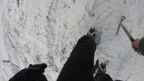 Feet-view-of-a-mountain-climber-in-the-swiss-alps-on-a-steep-glacier,-with-all-the-equipement:-snowpick,-rope-and-shoes