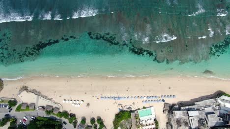 Drone-footage-of-MELASTI-BEACH-in-ULUWATU-BALI,-where-numerous-sunshades,-hotels,-and-waves-that-were-headed-toward-the-beach-could-be-seen