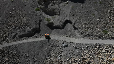 Cinematic-downward-angle-drone-shot-of-a-Tuk-Tuk-driving-on-a-small-gravel-path-in-the-Gojal-valley-upper-Hunza-of-the-Gilgit-Baltistan,-Pakistan