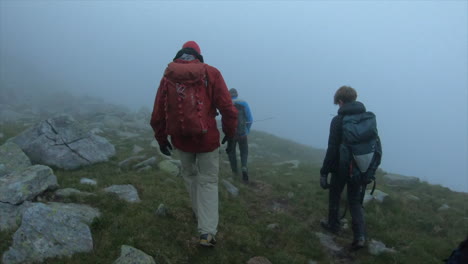A-group-of-mountain-climbers-with-backpacks-are-in-a-morning-fog-on-an-alpine-path-in-the-morning,-swiss-alps
