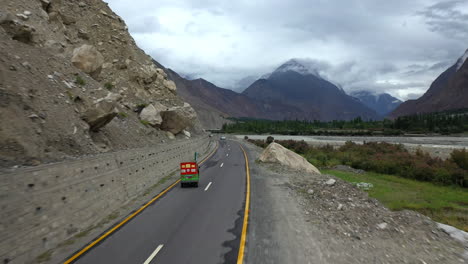 Dramatic-drone-shot-chasing-a-tuk-tuk-on-the-Karakoram-Highway-Pakistan-along-the-Hunza-river
