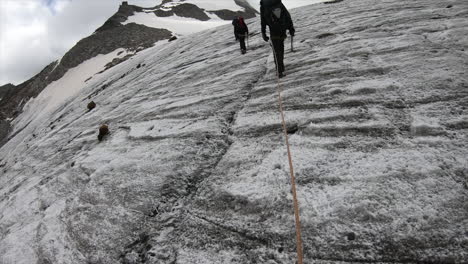 Mountaineers-walk-on-a-steep-glacier-in-the-Swiss-alps-mountains-to-find-crystal-in-the-rock-with-their-equipement,-helmet
