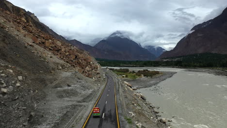 Dramatic-drone-shot-following-a-tuk-tuk-on-the-Karakoram-Highway-Pakistan-along-the-Hunza-river