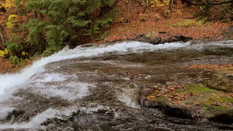 Ein-Bach,-Der-über-Moosige-Felsen-Auf-Dem-Blattbedeckten-Herbstwaldboden-Fließt