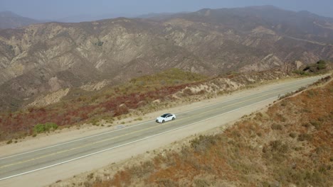 Sedan-driving-along-massive-canyon-scenic-view