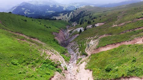 Berglandschaft-Der-Schlucht-Zwischen-Schrägen-Grünen-Hügeln,-Absteigender-Drohnenflug