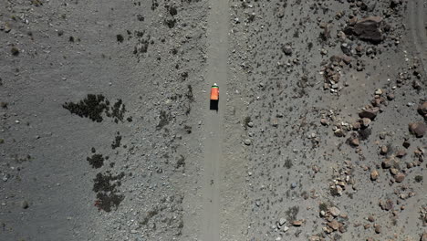 Dramatic-downward-angle-drone-shot-of-a-Tuk-Tuk-driving-on-a-small-gravel-path-in-the-Gojal-valley-upper-Hunza-of-the-Gilgit-Baltistan,-Pakistan