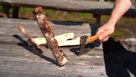 Hatchet-splitting-birch-firewood-log-on-wooden-table-in-slow-motion---Static-nature-clip-in-strong-sunlight