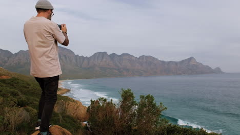 Caucasian-man-taking-pictures-of-ocean-from-vantage-point,-South-Africa