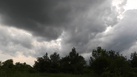 Zeitraffer-Von-Dicken-Dunklen-Wolken,-Die-Sich-über-Die-Silhouette-Von-Bäumen-Bewegen