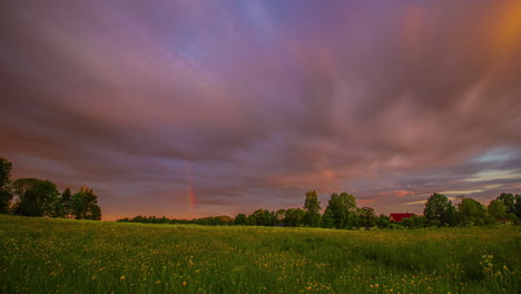 Timelapse-shot-Colourful-rainbow-fading-away-on-a-cloudy-day-over-green-grasslands