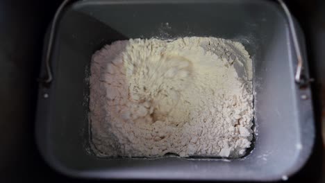 Top-down-view-of-bread-machine-mixing-flour-and-ingredients-to-make-dough