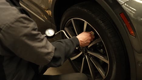 Mechanic-checking-tire-air-pressure,-panning-shot