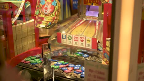 Arcade-coin-pusher,-woman-pointing-at-where-to-drop-the-coin,-slow-motion