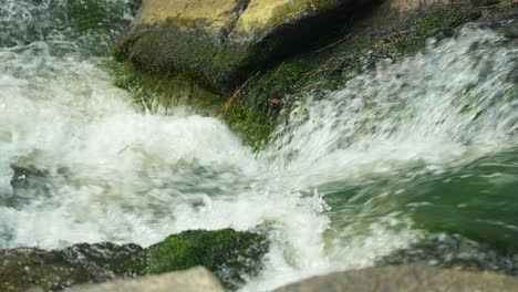 Close-up-of-a-clear-stream-moving-quickly-between-two-rocks-in-slow-motion