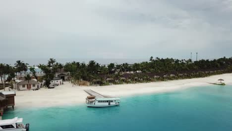 Drohnenaufnahme-Einer-Yacht-In-Einem-Malediven-Resort-Mit-Palmen-Und-Villen