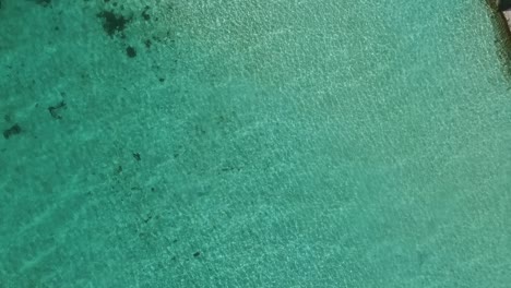 Drone-shot-above-clear-blue-water-in-a-Maldives-resort