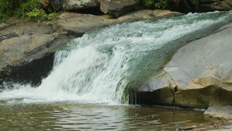A-fast-moving-stream-rolls-off-a-rock-ledge-into-a-large-body-of-water